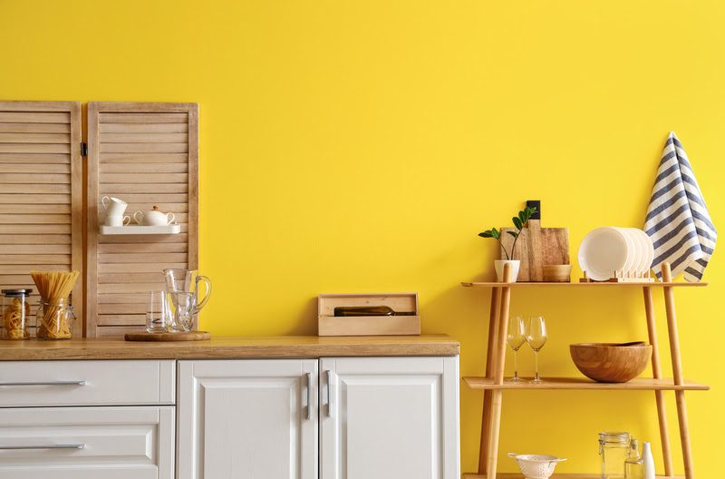Cozinha com parede amarela e armário branco
