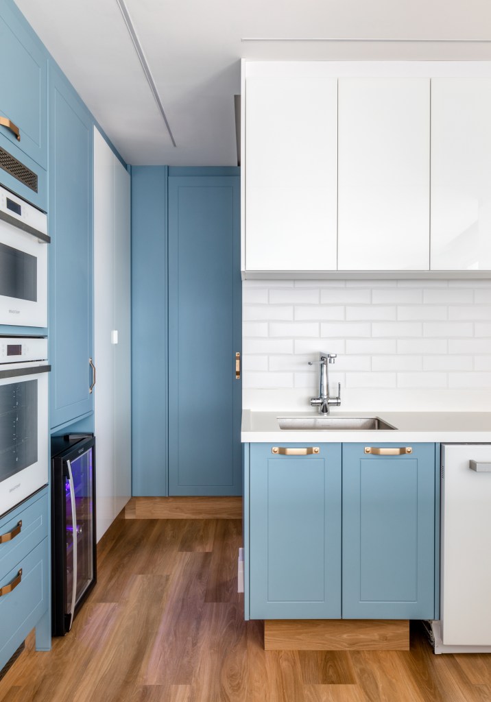 Cozinha com marcenaria azul e backsplash de tijolinhos brancos.