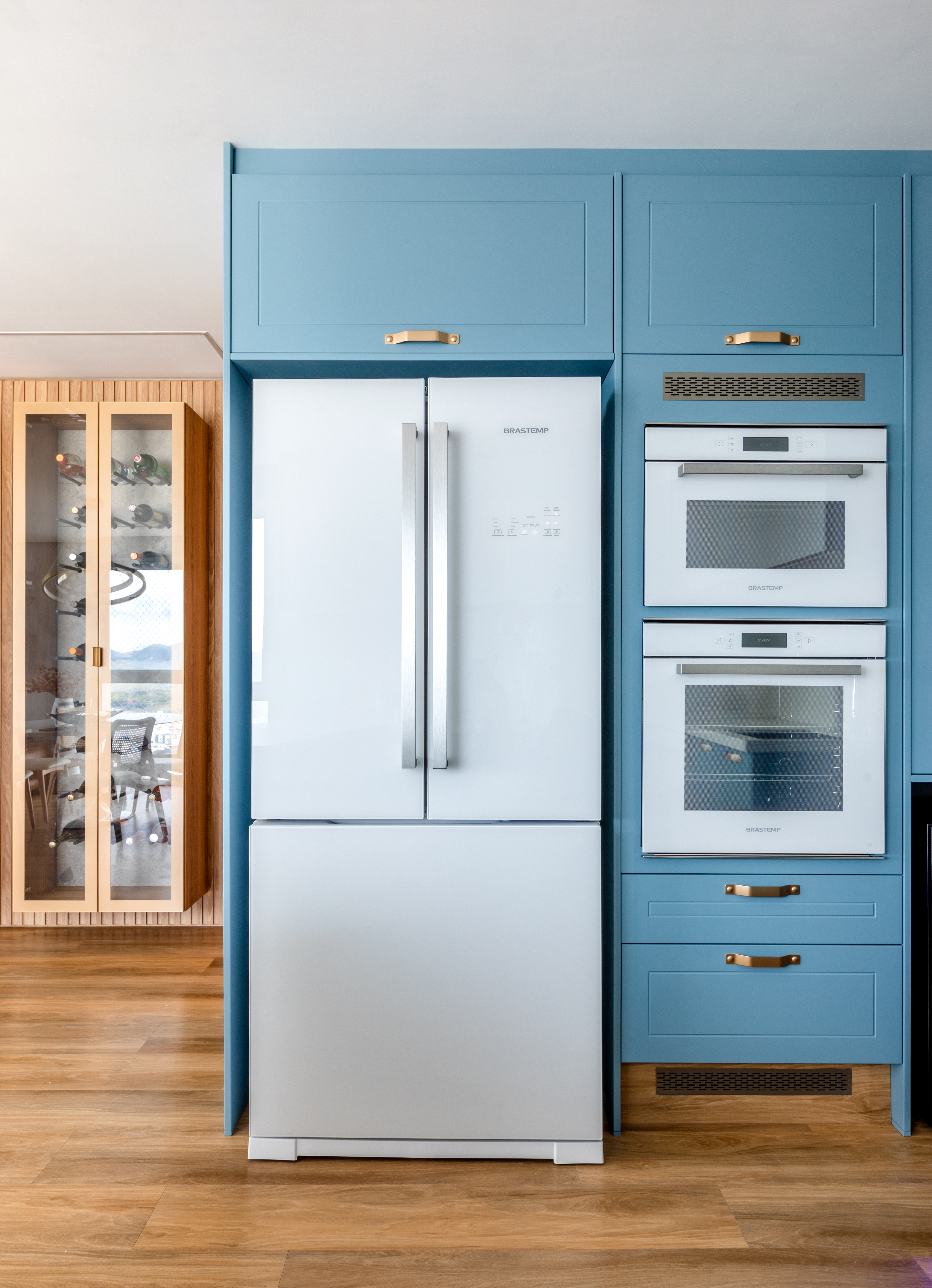 Cozinha com marcenaria azul e geladeira de duas portas