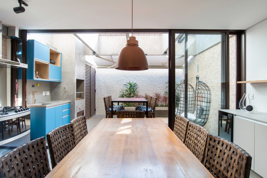Cozinha com marcenaria azul com mesa de madeira voltada para quintal
