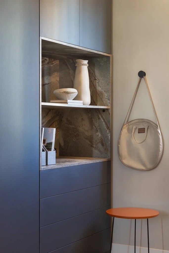 Home office com marcenaria e poltrona azul e gancho na parede.
