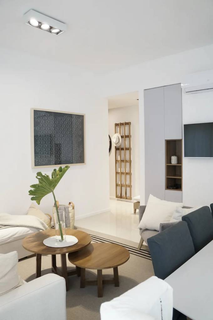Sala de estar branca com estrutura de madeira que serve como cabideiro.