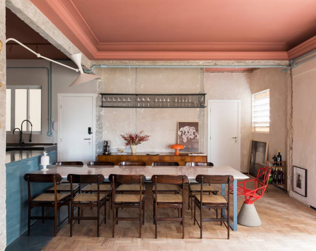 Sala de jantar com teto colorido rosa; mesa de jantar e cadeira de palhinha.
