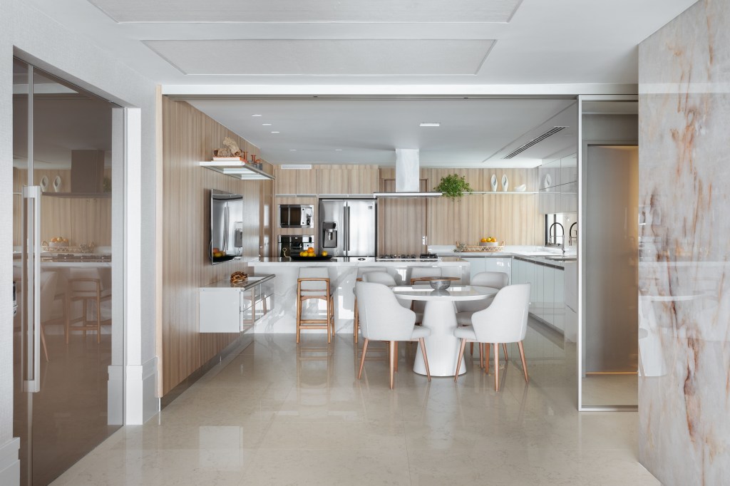 Cozinha integrada com marcenaria branca e porta de correr.