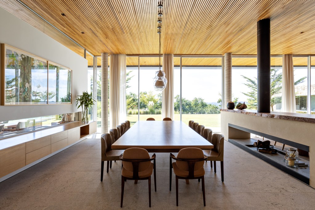 Sala de jantar com mesa de madeira e portas de vidro com vista para jardim