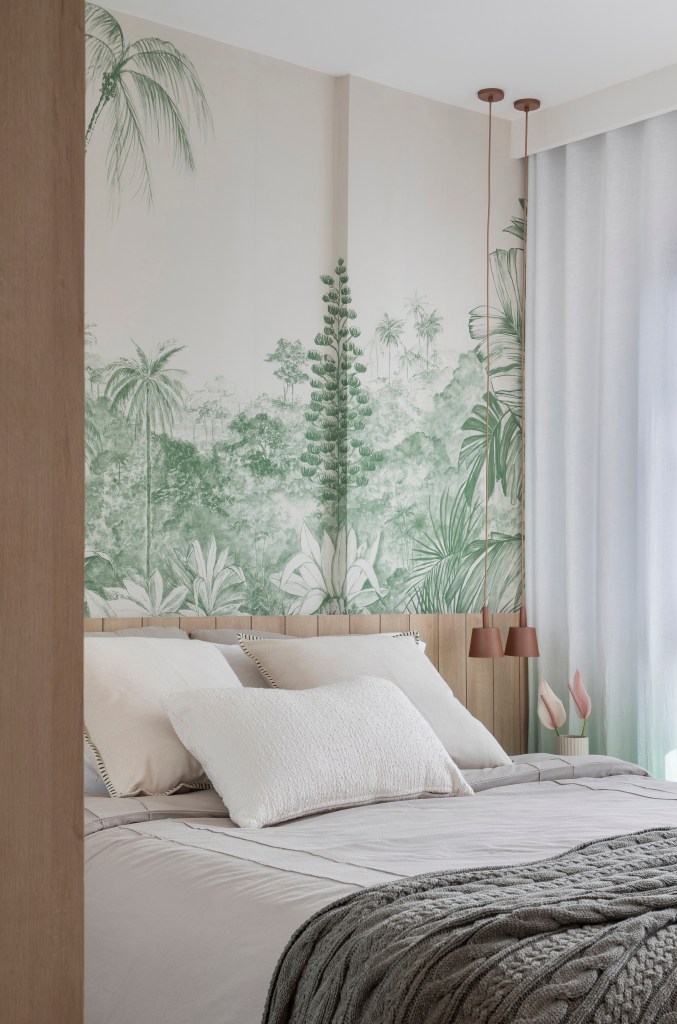 Quarto com cama de casal e papel de parede com plantas.