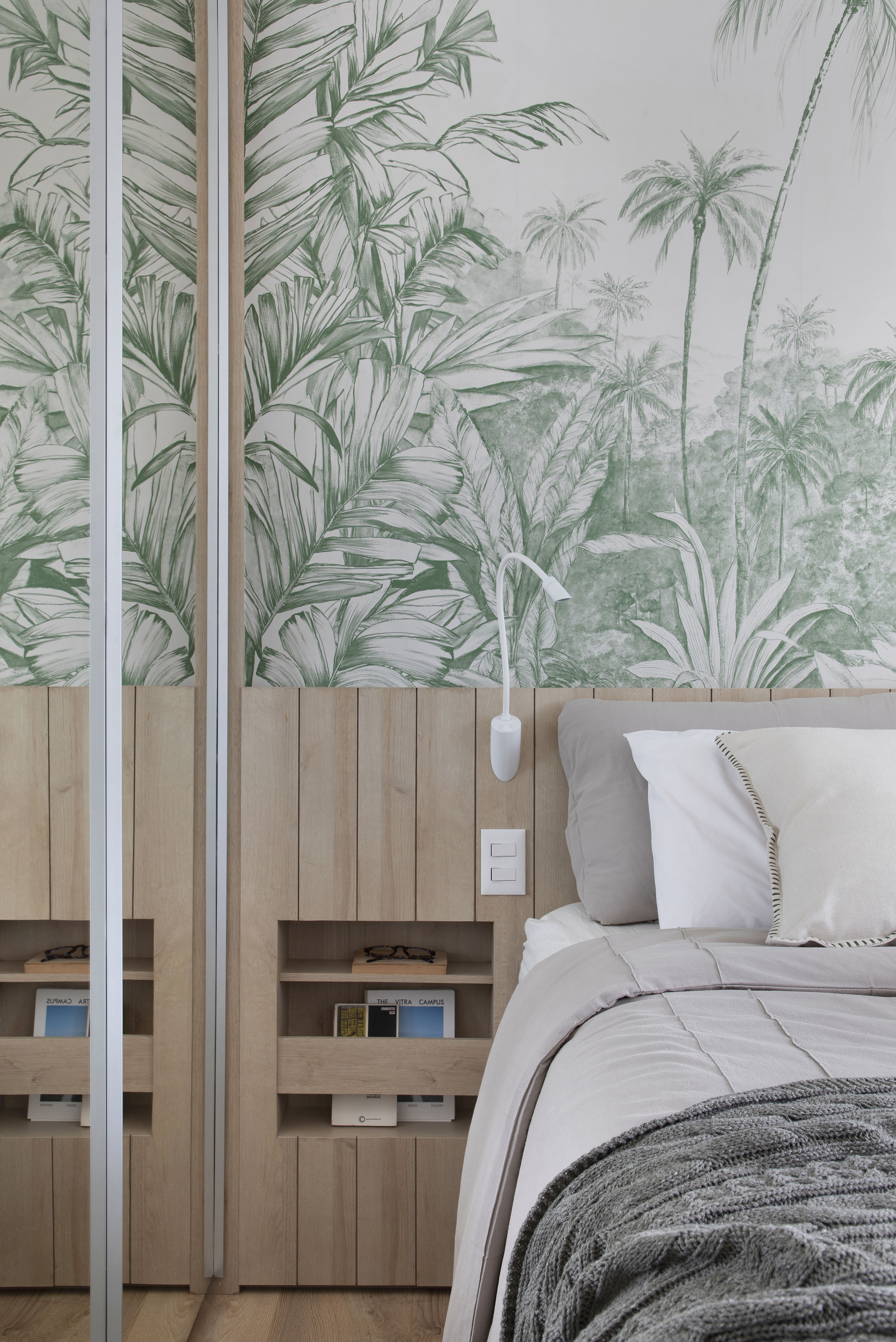 Quarto com cama de casal e papel de parede com plantas.