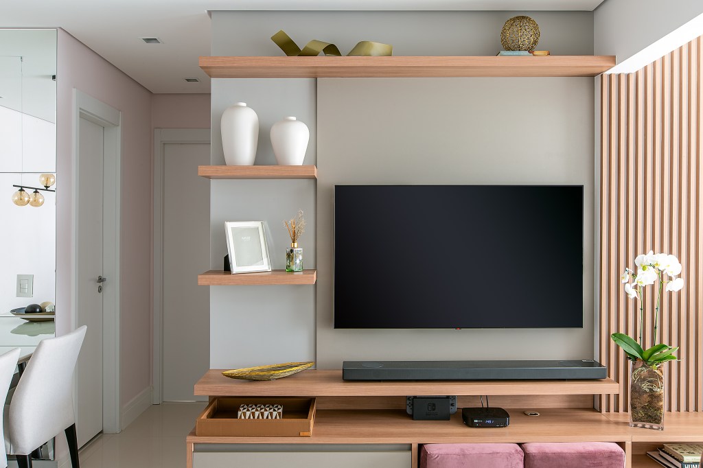 Sala de tv com rack de madeira e prateleiras.