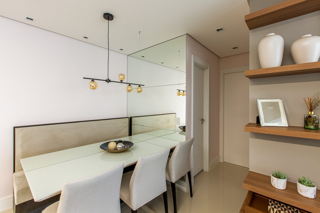 Sala de jantar com parede espelhada, mesa branca, cadeiras e branco.