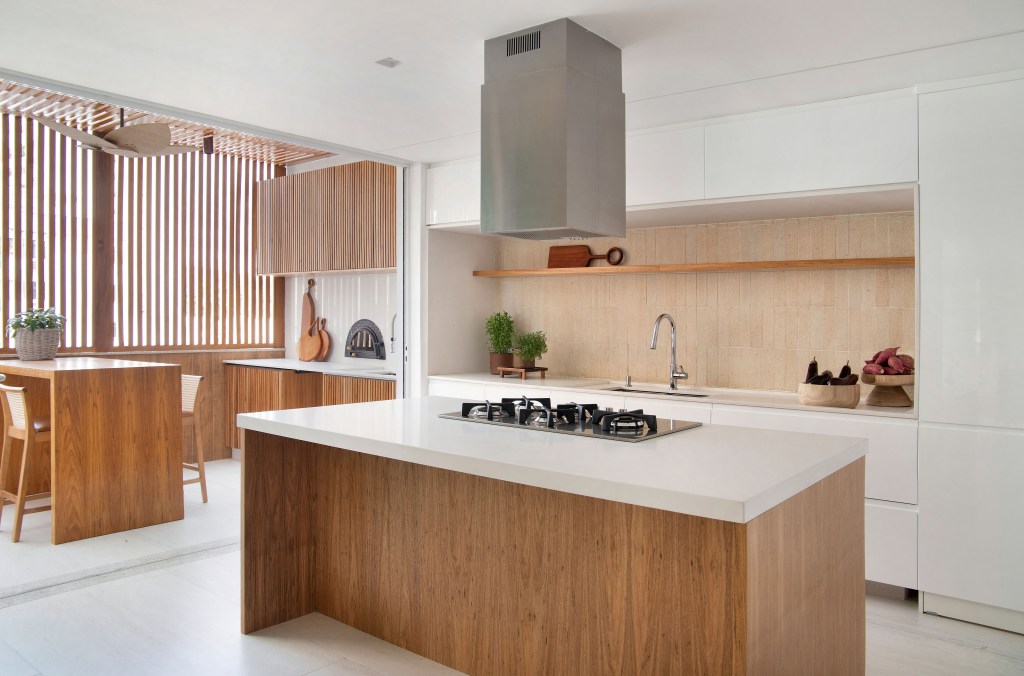 Cozinha branca e minimalista com ilha em madeira; cozinha integrada;