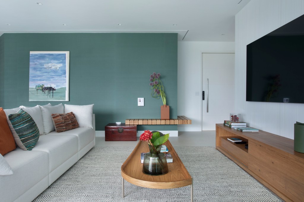 Sala de tv com parede verde e mesa de centro de madeira.