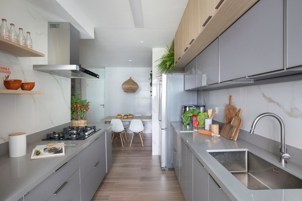 Cozinha com piso revestido de porcelanato no padrão madeira e marcenaria cinza clara.