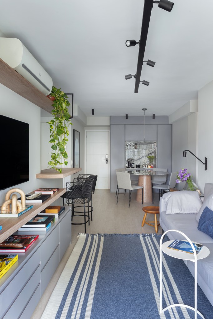 Sala de estar pequena; sala de estar estreita com sofá cinza e tapete azul; iluminação com trilhos de spots