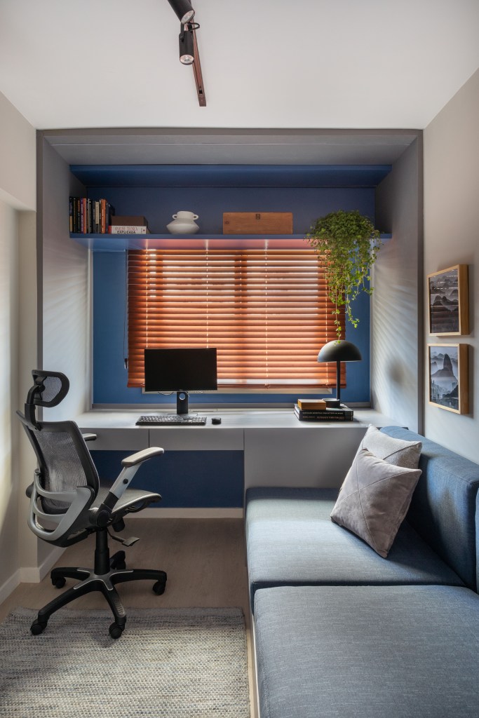Home office com parede azul e sofá cama.