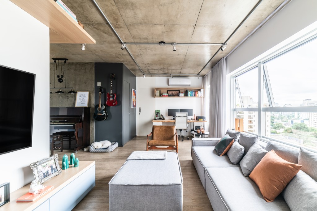 Sala de estar em estilo industrial com sofá modular cinza.