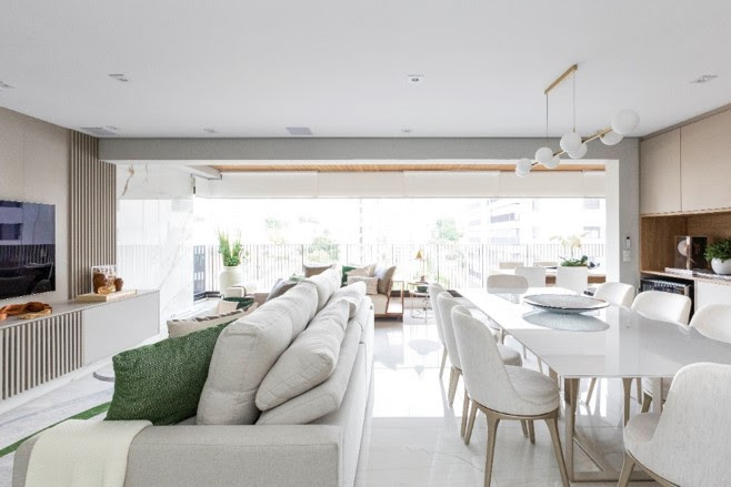 Sala de estar, jantar e varanda integradas com sofá retrátil branco.