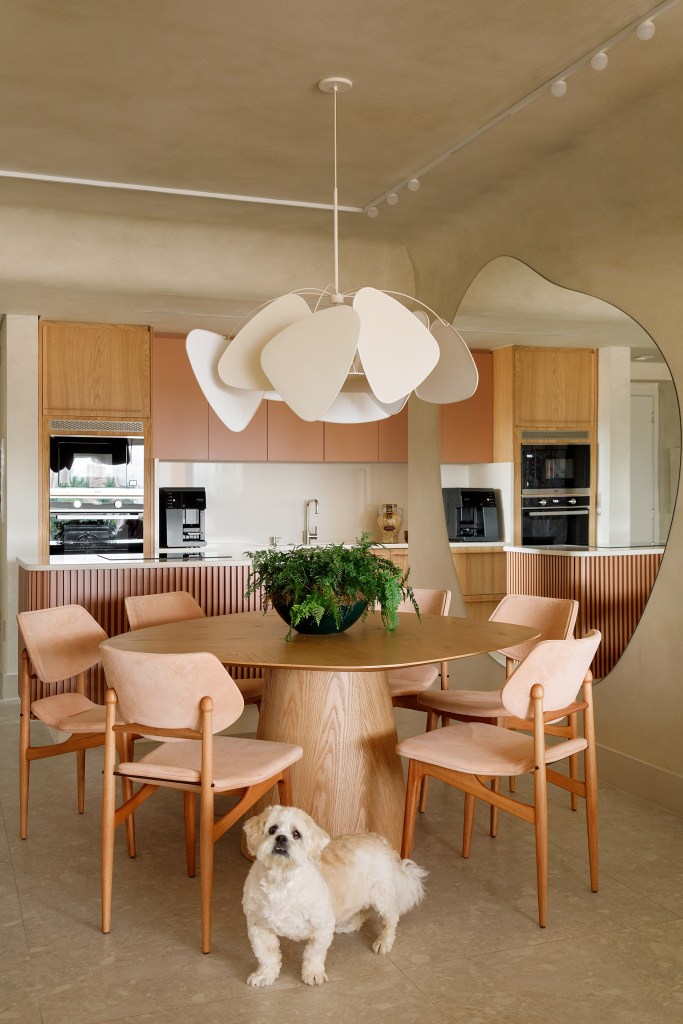 Sala de jantar integrada com cozinha; mesa redonda, cadeiras de madeira e luminária.