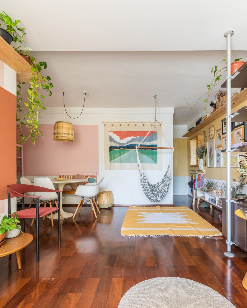 Sala de estar e jantar integradas com piso de madeira e paredes coloridas.
