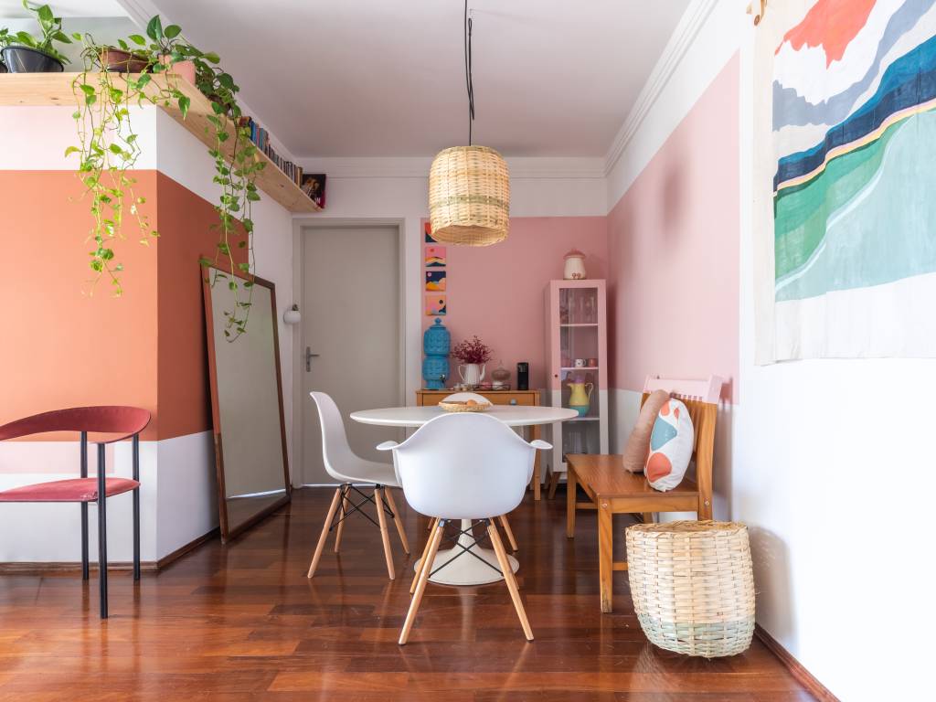 ape-80m-decoracao-memorias-paleta-de-cores-terrosa-sertao-arquitetos-05-sala-jantar Sala de jantar com parede rosa, mesa redonda branca e luminária de palha.