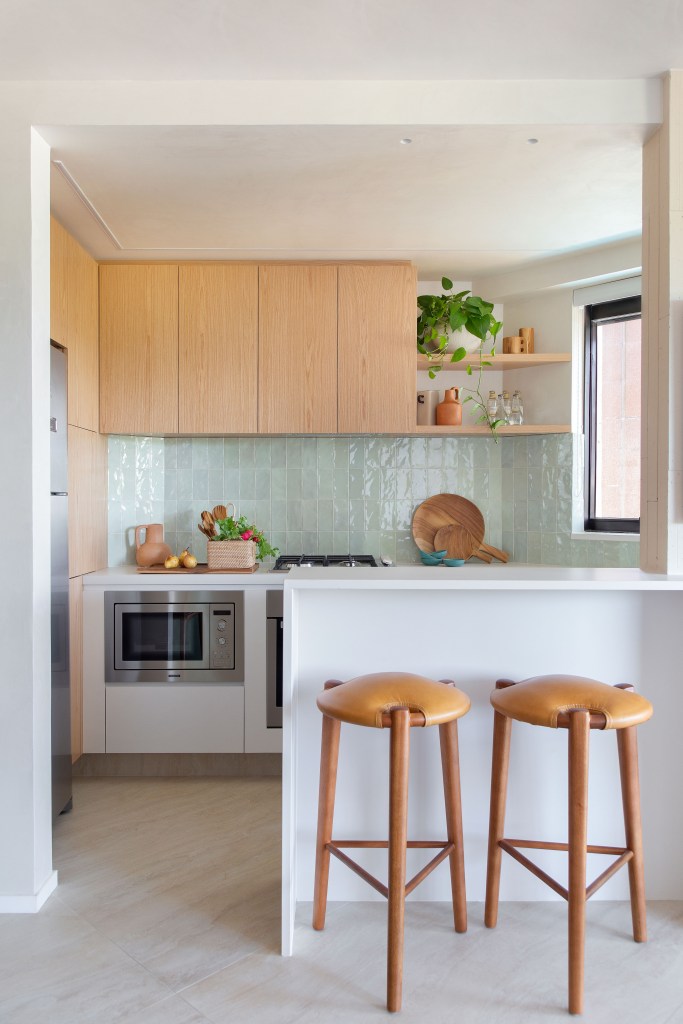 Cozinha americana; cozinha integrada com azulejos de madeira e bancada branca.
