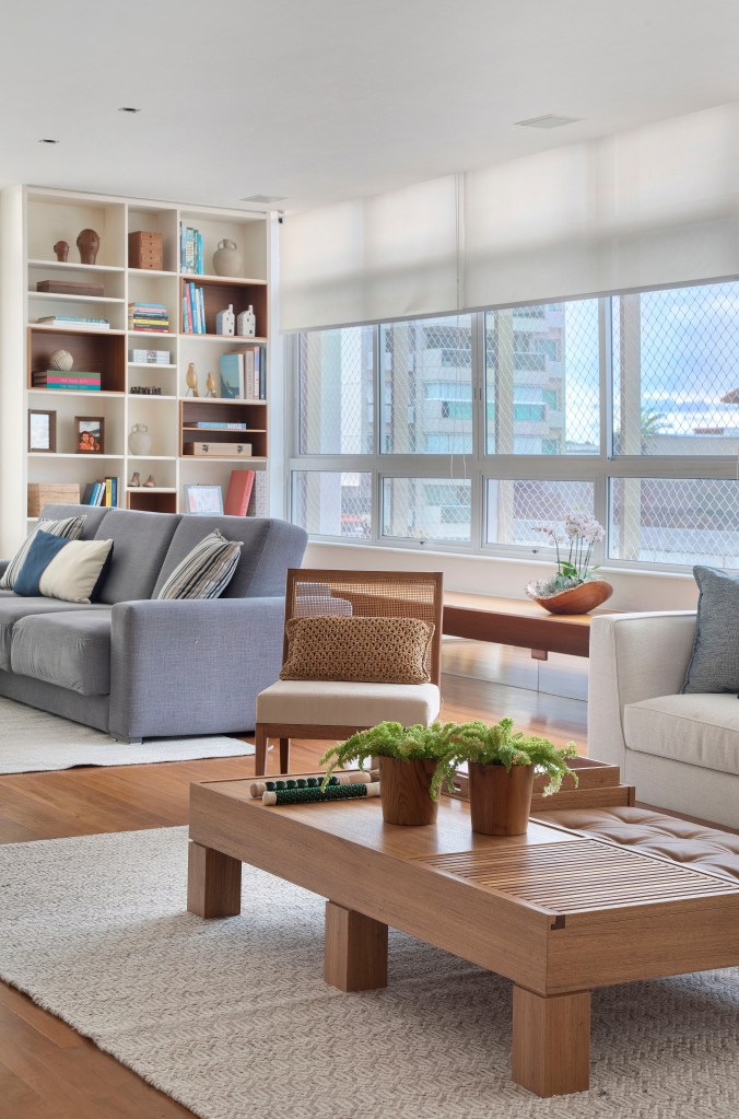 Sala de estar iluminada com piso de madeira, sofá azul e mesa de centro de madeira.