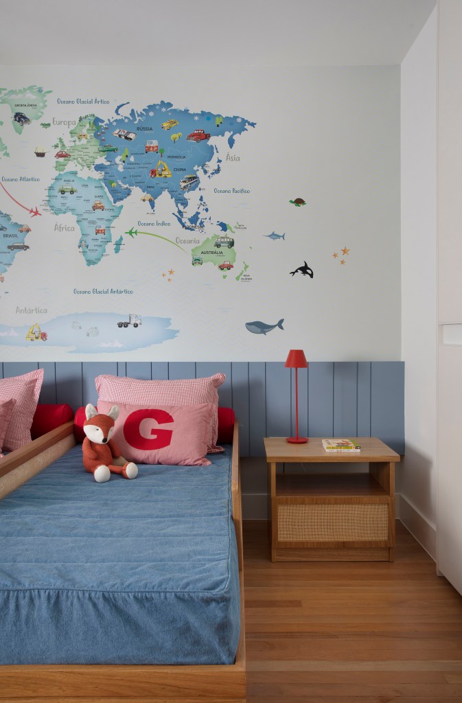 Quarto infantil com cabeceira azul, duas bicamas e mural de mapa múndi.