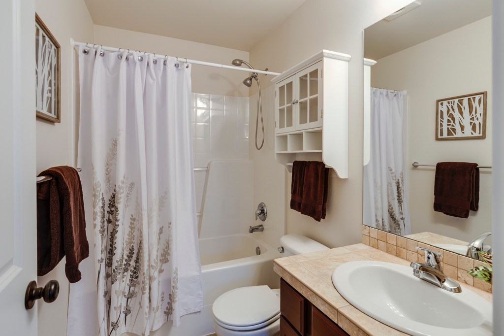 Banheiro americano com banheira e cortina.