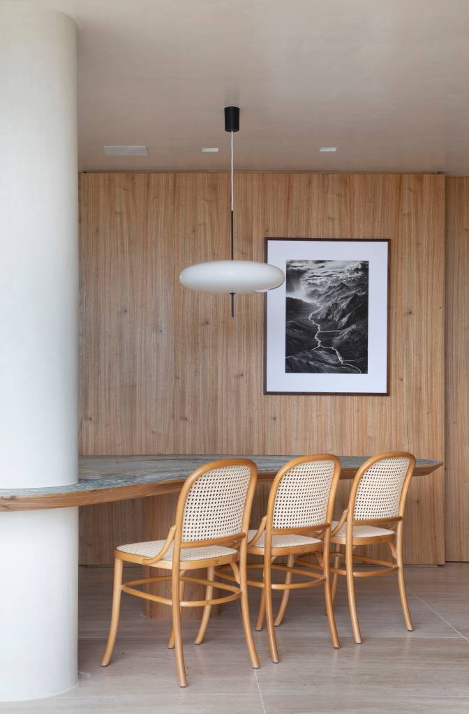 Sala de jantar com mesa com tampo de pedra e paredes revestidas de madeira.