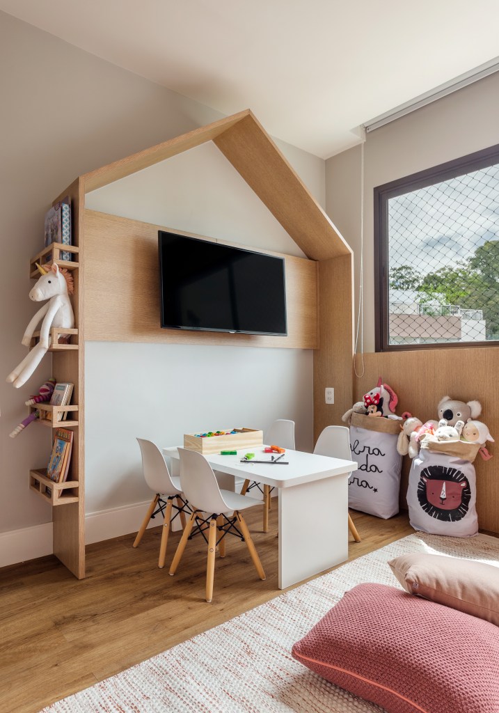 Quarto infantil de menina com cama baixa, papel de parede e marcenaria em forma de casinha.