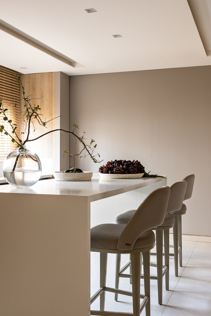 Cozinha layout clean elegante revestimento amadeirado Mota Arquitetura ilha bancada cadeiras vaso