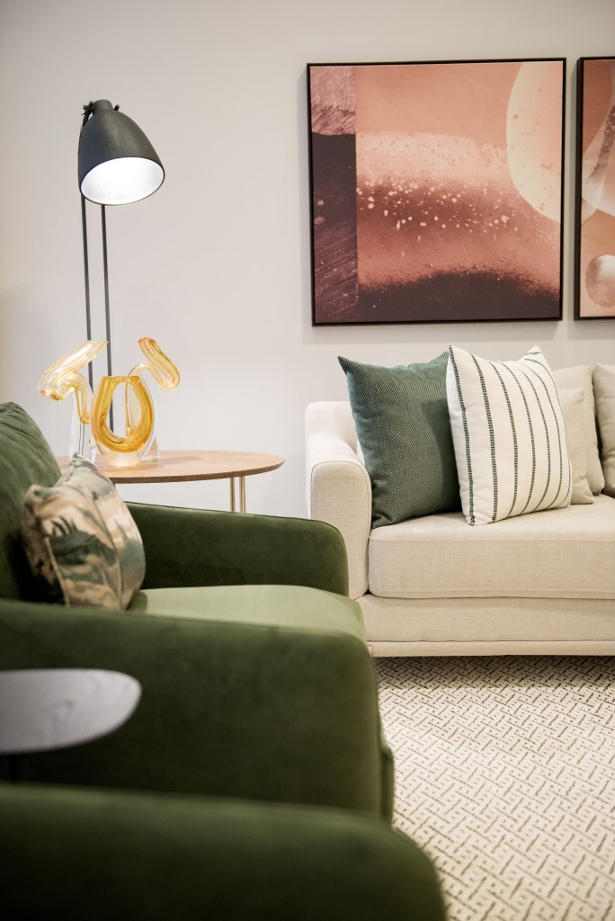 Sala de estar com sofá branco, poltrona verde e almofadas verdes.