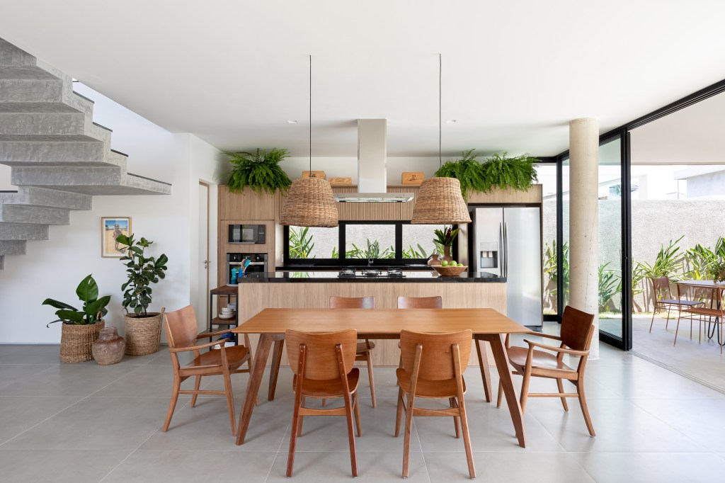 Sala de jantar integrada com cozinha; mesa de jantar de madeira