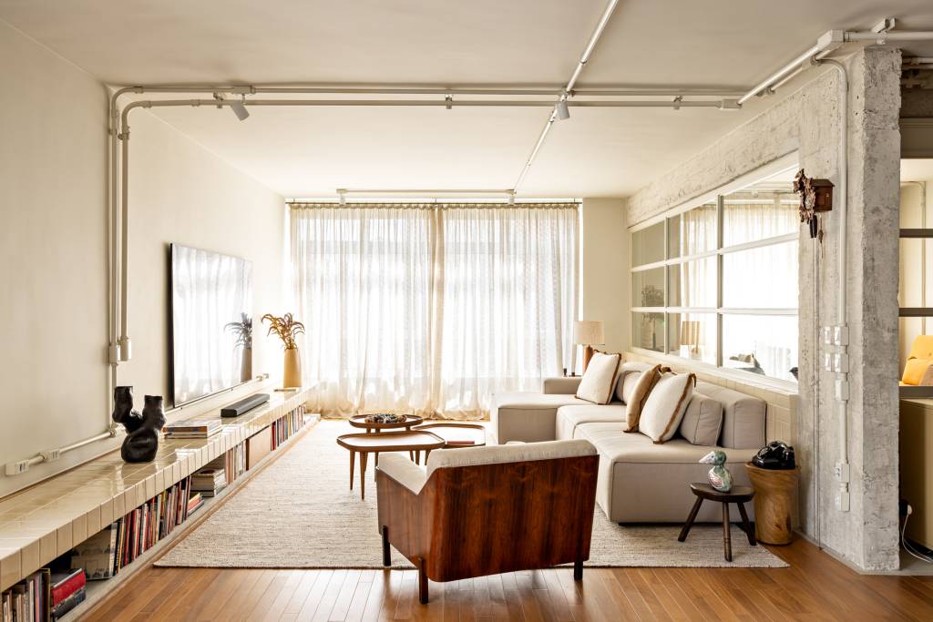 mescla-rustico-industrial-ape-167m-com-home-office-na-sala-memola-estudio-09 Sala de estar branca clara com cortina branca, sofá creme e tapete bege.
