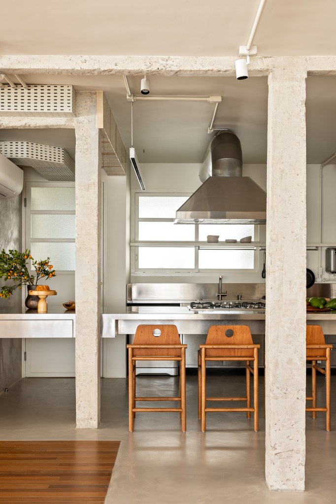 Cozinha integrada em estilo rústico e industrial com ilha, bancada e coifa.