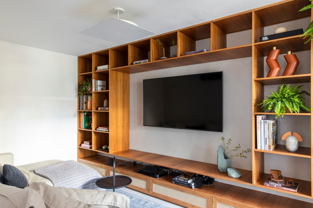 Sala de tv com estante de nichos de madeira.