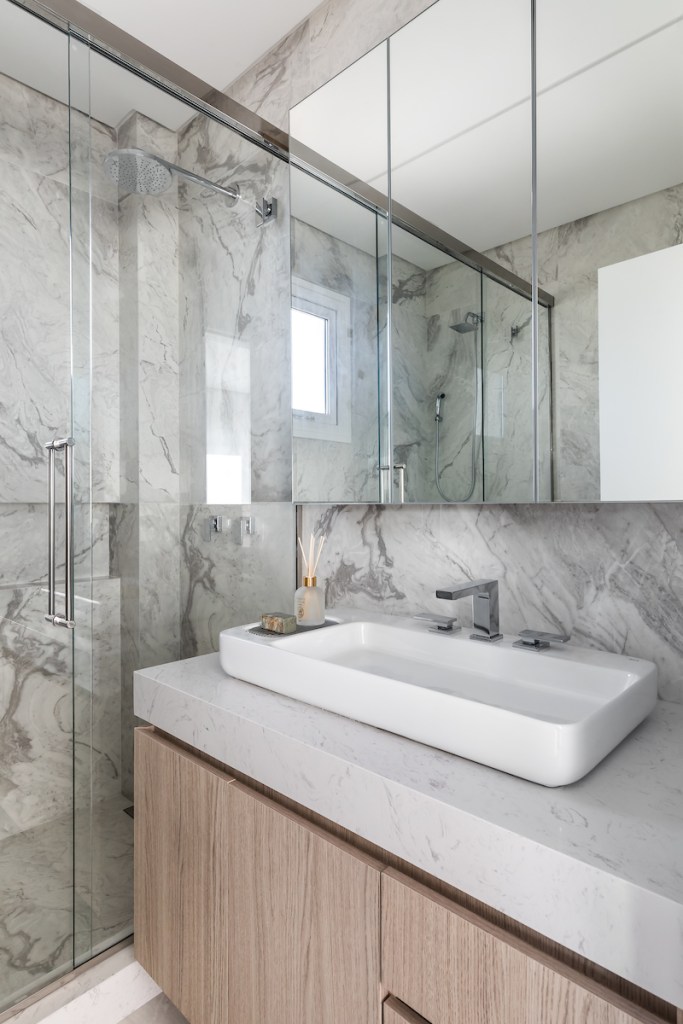 Banheiro pequeno com revestimento marmorizado e cuba solta.