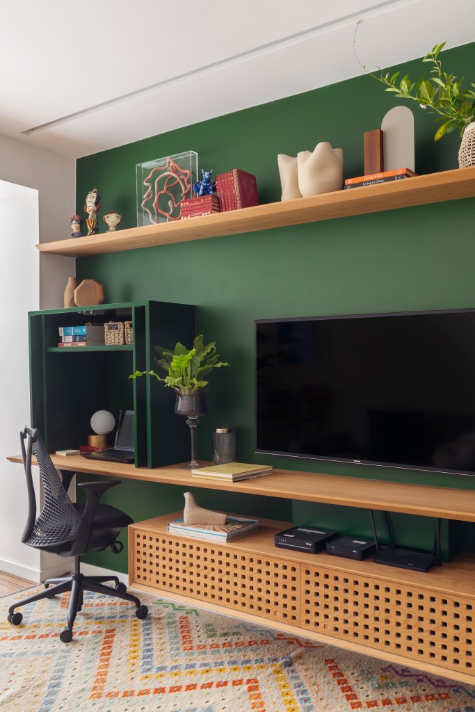 Home office pequeno em sala com parede verde.