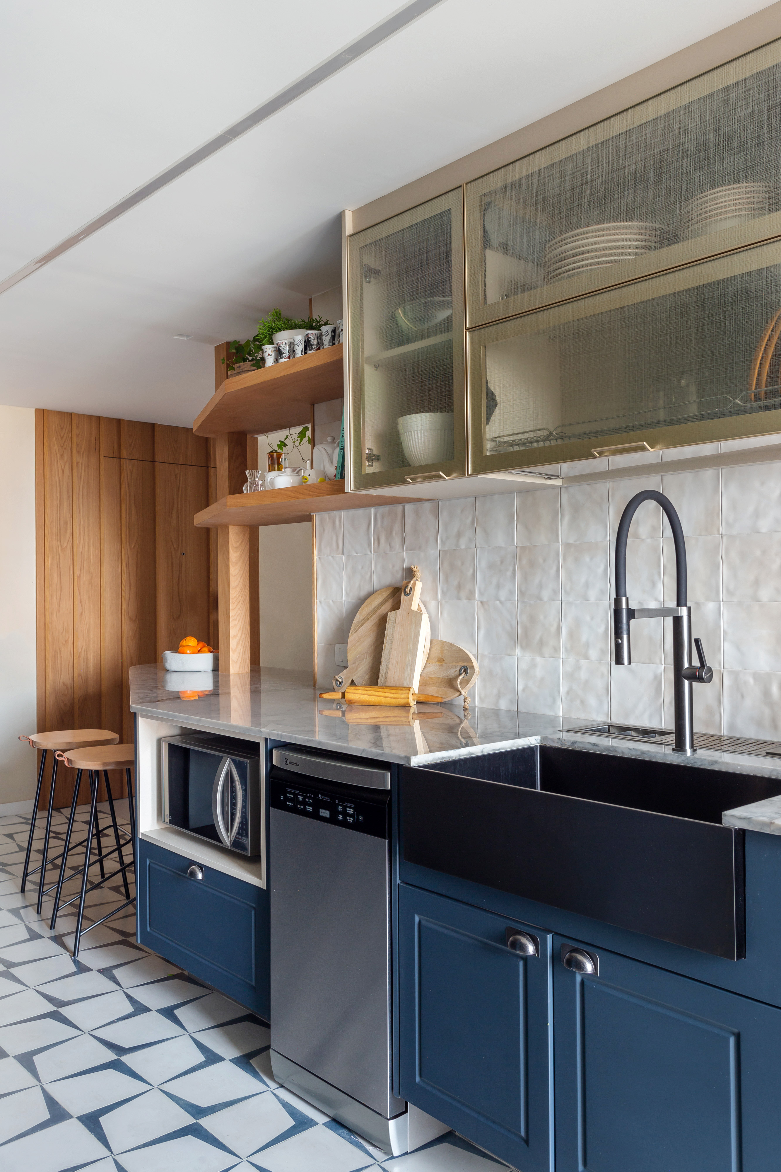 Cozinha integrada com piso de ladrilho hidráulico, armários com porta de vidro e marcenaria azul.