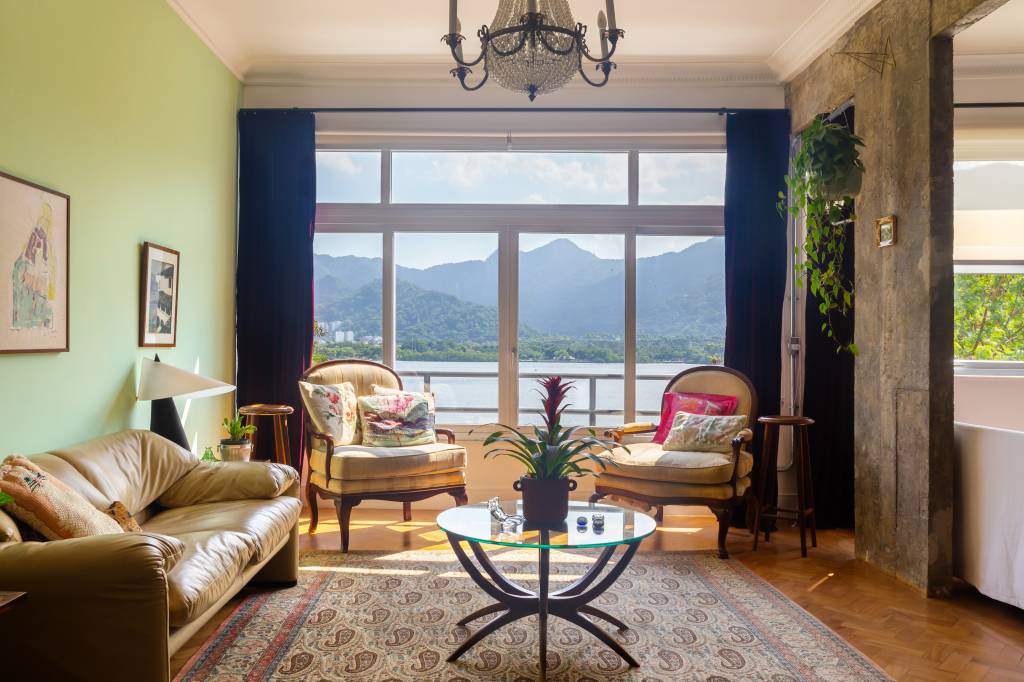 Sala de estar com decoração vintage, lustre e parede verde.