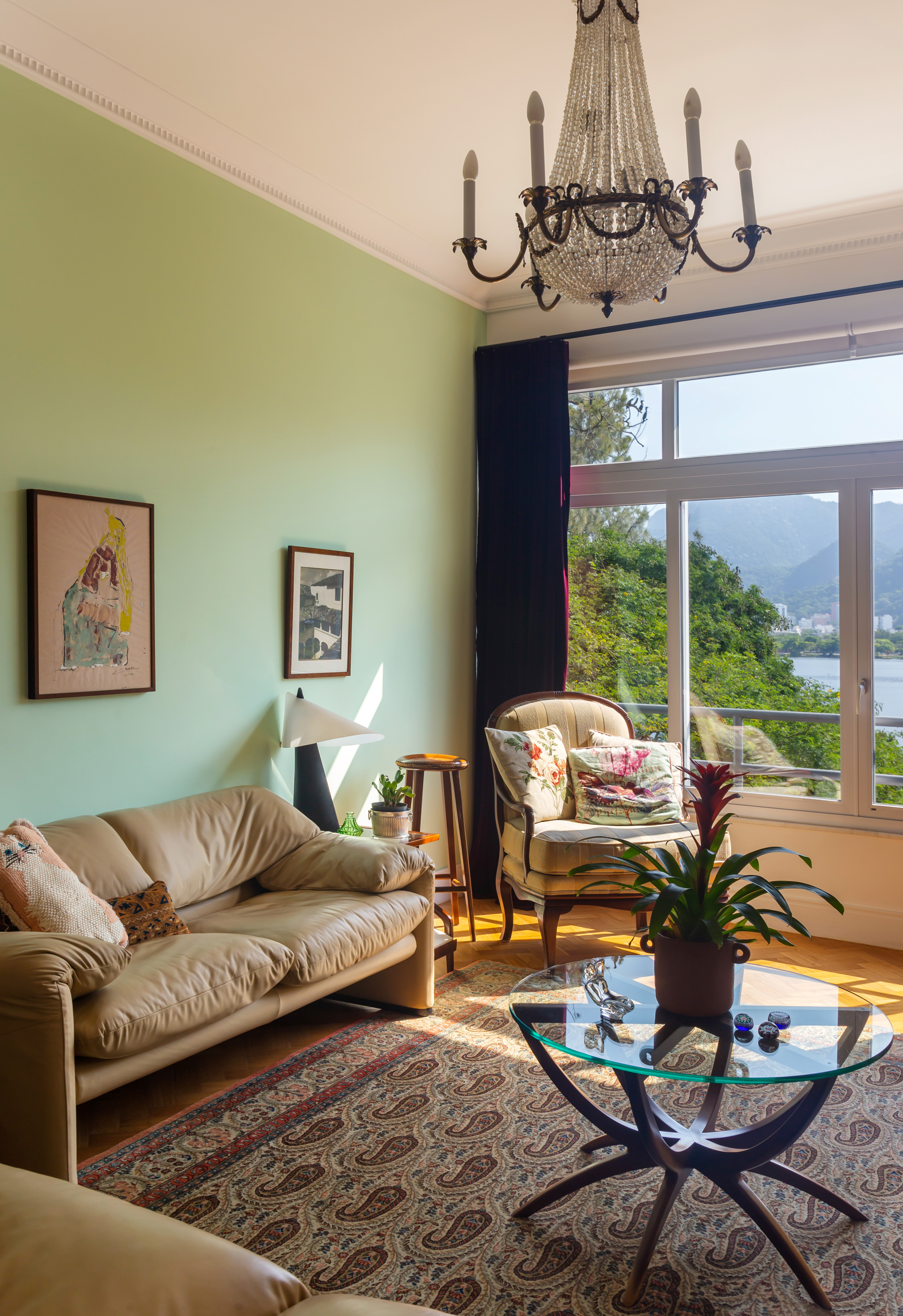 Sala de estar com decoração vintage, lustre e parede verde.