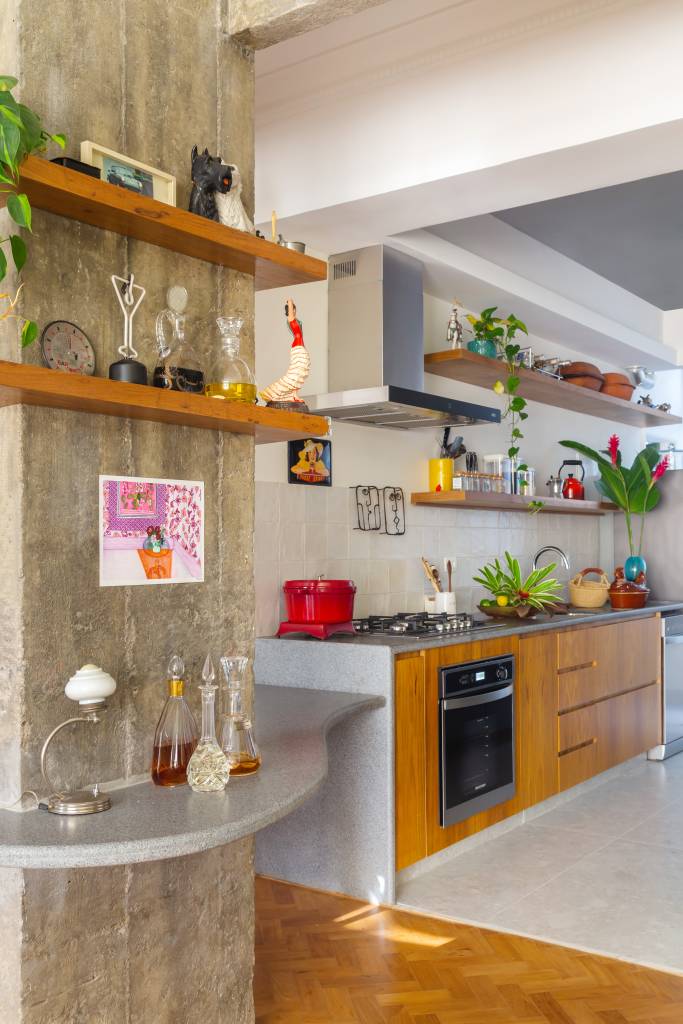 Sala com cozinha integrada; mesa de jantar em volta de pilar.