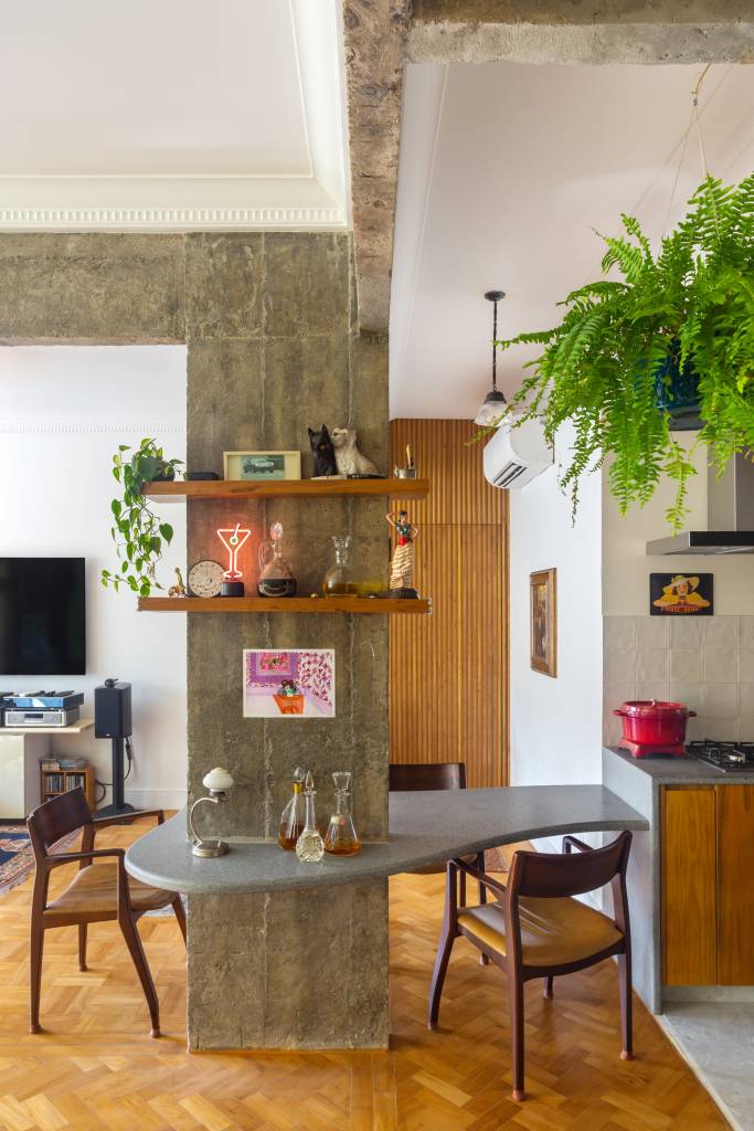 Sala com cozinha integrada; mesa de jantar em volta de pilar.