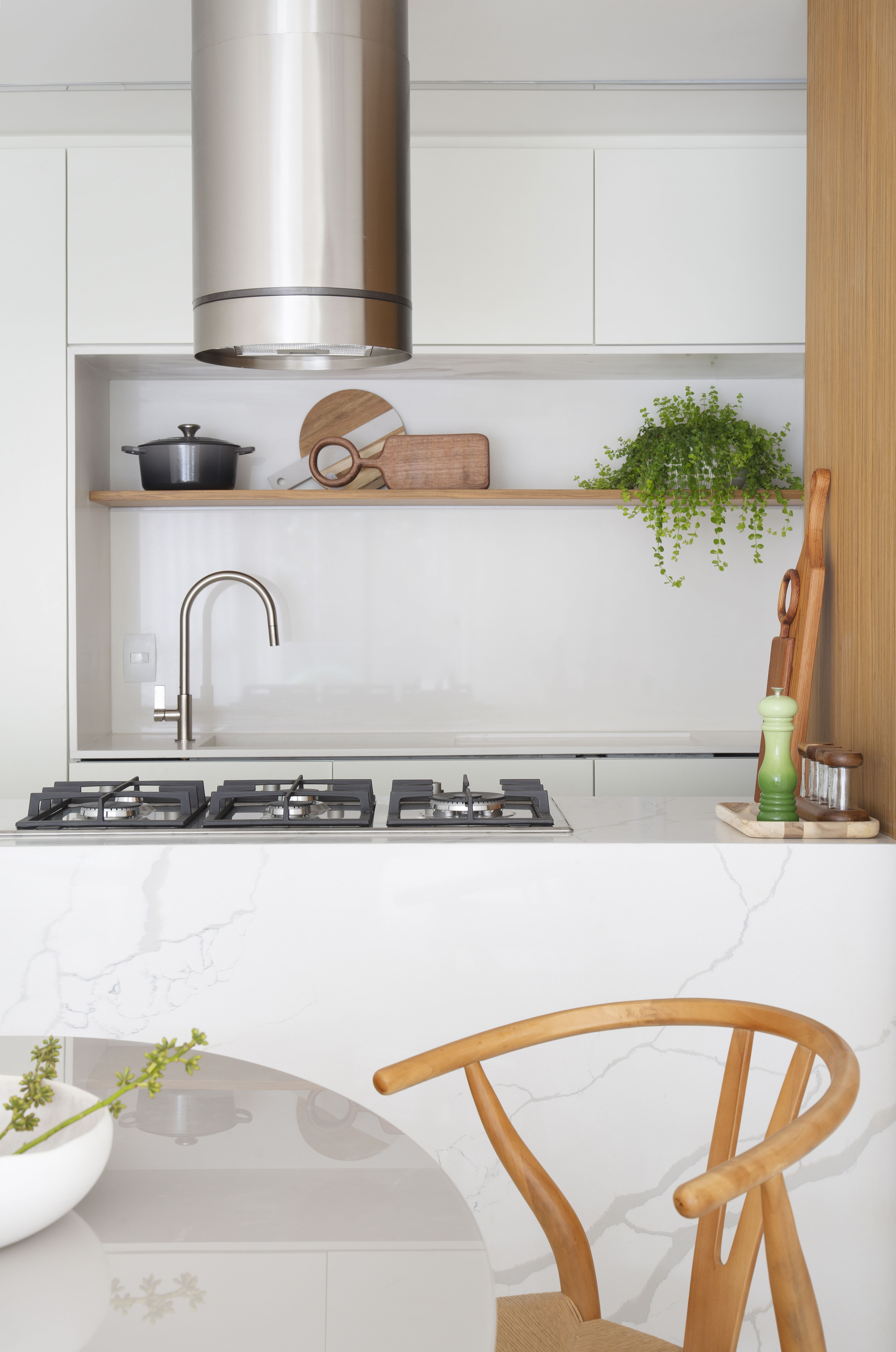 Cozinha integrada branca com ilha com revestimento marmorizado e coifa;
