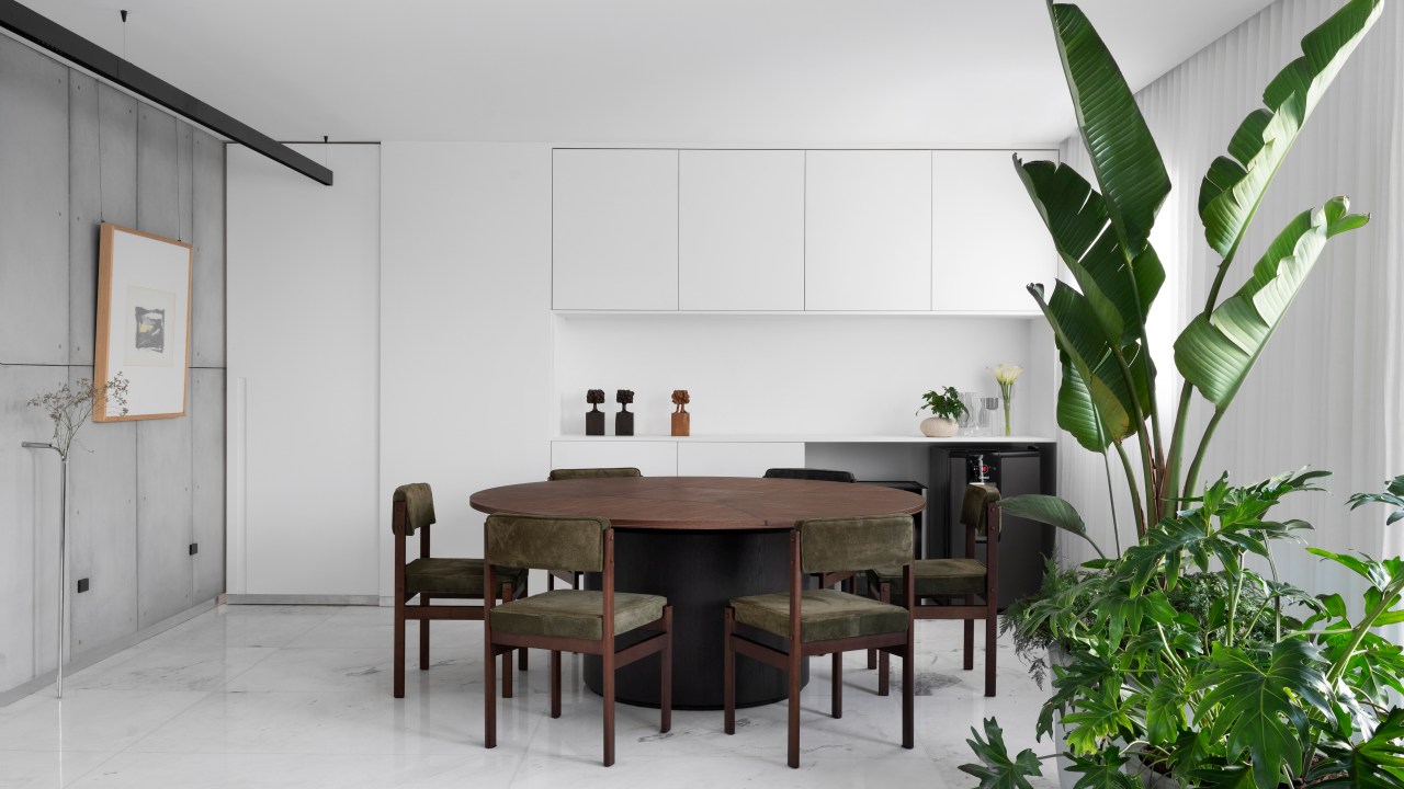Sala de jantar minimalista com piso branco e mesa redonda de madeira.