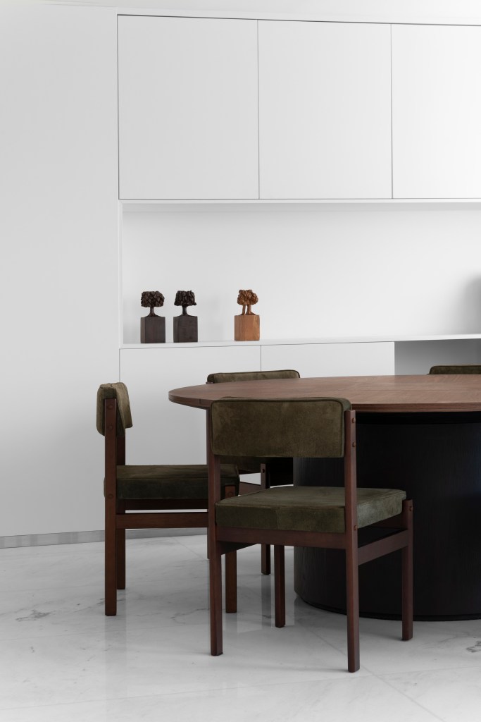 Sala de jantar minimalista com piso branco e mesa redonda de madeira.