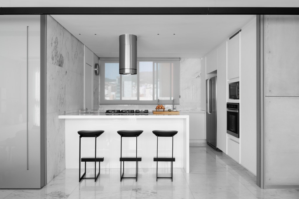 Cozinha branca minimalista com portas de correr e bancada branca.