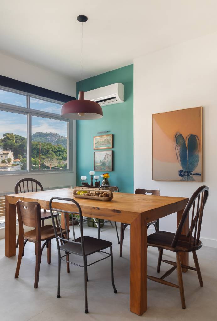 Sala de jantar com mesa de madeira e cadeiras de modelos diferentes.