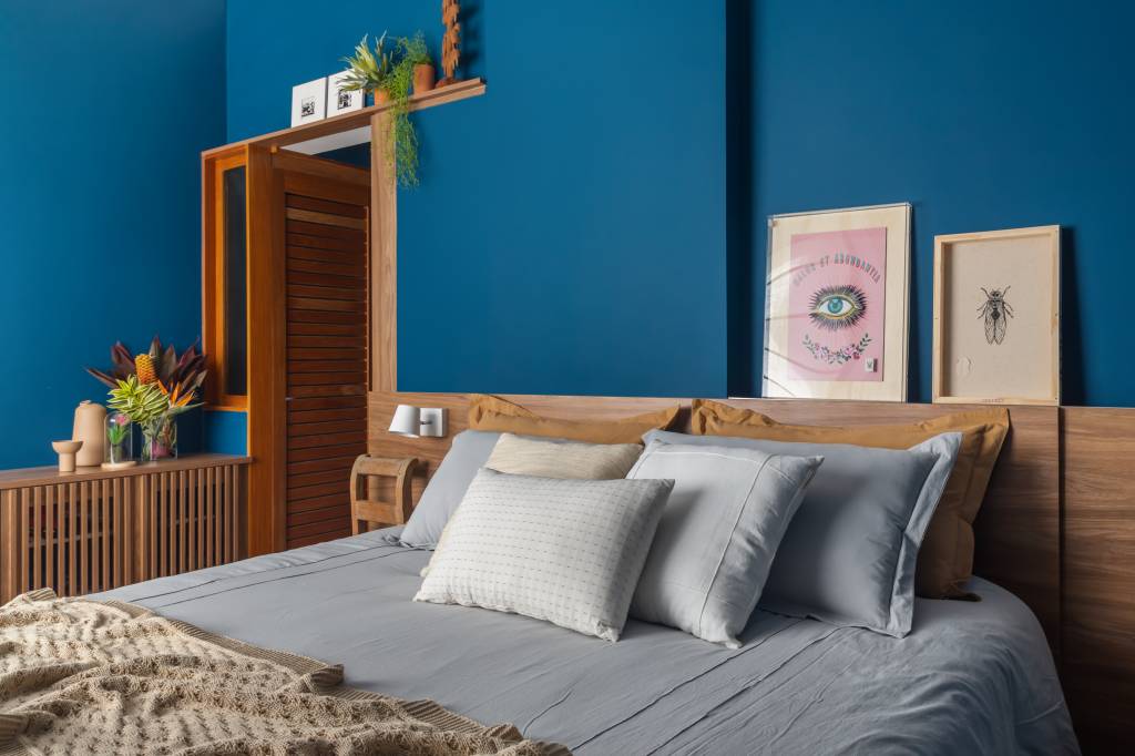 Quarto com parede azul e armário de madeira ripada.