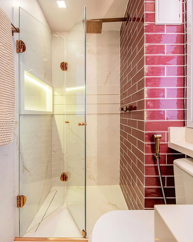 Banheiro com box de vidro e parede de tijolinho rosa