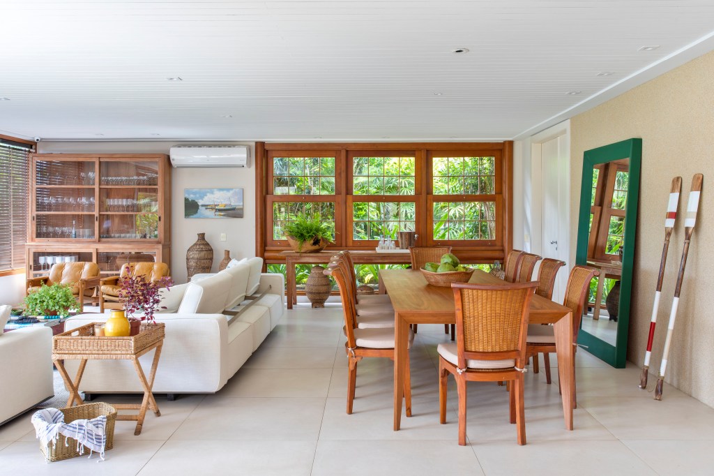 Sala de estar e jantar integradas; piso de porcelanato, mesa de madeira e sofá branco